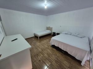 a white bedroom with a bed and a desk at Pousada Maria in Maravilha +6 photos
