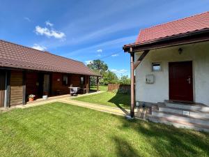 a house with a grass yard next to a building at Zagroda u Leny - Dom na wyłączność in Czyże