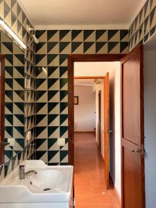 a bathroom with a sink and a black and white tiled wall at Tramuntana Sunset in Port de Soller