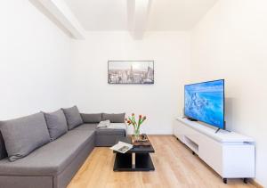 a living room with a gray couch and a flat screen tv at Calm Center Modern Apartment in Staré Mesto