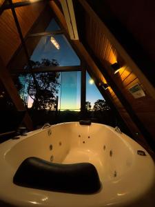 a bath tub in a room with a large window at Chalés Villa Alecrim COM HIDROMASSAGEM E AR CONDICIONADO in Campos do Jordão