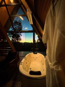 a bathroom with a bath tub and a window at Chalés Villa Alecrim COM HIDROMASSAGEM E AR CONDICIONADO in Campos do Jordão