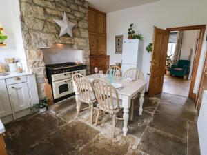 a kitchen with a table and chairs and a stone wall at Snowdrop Cottage in Keighley