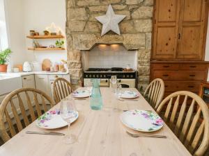 a wooden table with plates and glasses on it in a kitchen at Snowdrop Cottage in Keighley +19 photos