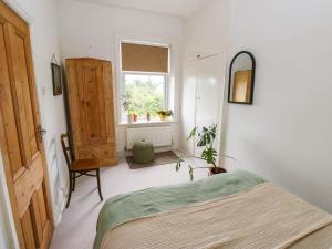 a bedroom with a bed and a window and a chair at Snowdrop Cottage in Keighley