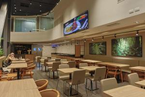 a restaurant with tables and chairs and a tv at Ibis Maringa in Maringá