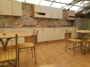 a kitchen with white cabinets and wooden tables and chairs at Мини отель Семейного типа. in Zatoka