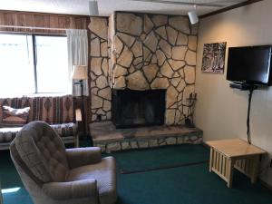 een woonkamer met een stenen open haard en een televisie bij Ponderosa Lodge, an Ascend Collection Hotel in Red River