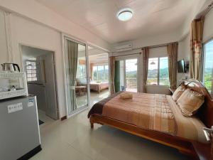 a bedroom with a bed and a tv and some windows at บ้านสุขอรุณ เขาค้อ Baan Sook A Roon KhaoKho in Khao Kho