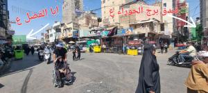 a group of people walking down a busy city street at فندق برج الحوراء ع in Karbala