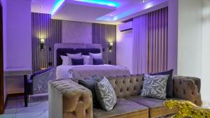 a bedroom with a couch and a bed with purple lighting at The ATRIUM BOUTIQUE HOTEL in Polokwane