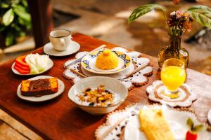 a table with plates of food and a vase of orange juice at Preá Kite House in Prea +24 photos