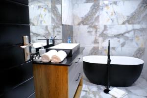 a bathroom with a black and white tub and a sink at The ATRIUM BOUTIQUE HOTEL in Polokwane