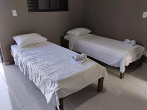 two beds with white sheets in a room at Pousada e Restaurante Jacuba in Arealva