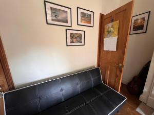 a black leather couch in a room with pictures on the wall at Relax in a Creative Art Space in Guildford