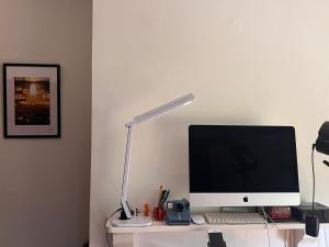 a computer monitor sitting on a desk with a lamp at Relax in a Creative Art Space in Guildford