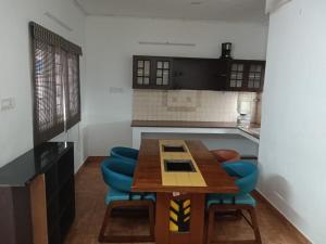 a kitchen with a wooden table and blue chairs at Adory homes inn in Kelambākkam