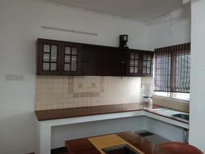 a kitchen with wooden cabinets and a counter top at Adory homes inn in Kelambākkam +20 photos