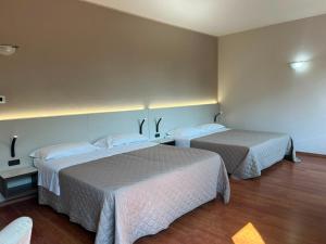 a hotel room with two beds with white sheets at Il Grifo Hotel e Bisteccheria Toscana in Montepulciano