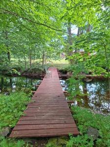 a wooden bridge over a river with two chairs on it at Frida in Filipstad