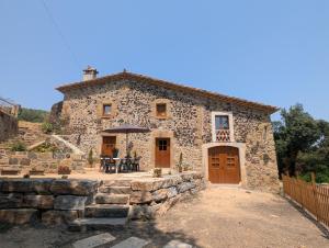 a stone house with a table and an umbrella at Can Quel in Canet de Adri