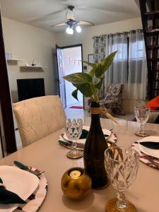 a dining room table with a vase with a plant in it at Casa à Beira Mar em Praia Seca Araruama RJ in Araruama