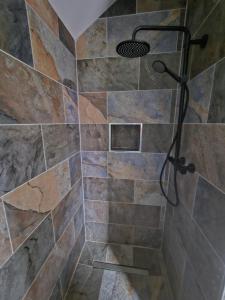 a shower in a bathroom with a stone wall at Suaimhneas in Lahinch