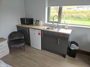 a kitchen with a sink and a chair and a window at Suaimhneas in Lahinch