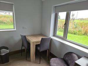 a room with a table and chairs and two windows at Suaimhneas in Lahinch +3 photos