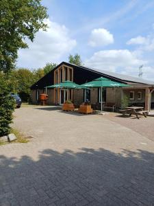 a building with green umbrellas and a picnic table at Buitengewoon Overnachten in Terheijden