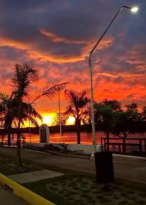 a sunset with palm trees and a street light at Esquina Hostel in Esquina