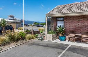 a red brick house with a bench and a table at Foreshore Motor Lodge in Lower Hutt