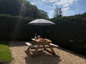 a picnic table with an umbrella and a bottle of wine at Saddleback Bungalow in Llandrindod Wells