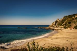 a sandy beach with the ocean and a hill at Il Pero Selvatico in Borgia