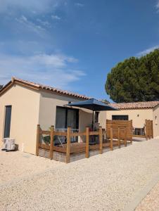a house with a wooden fence and an umbrella at Chic and Chill Guest House, gite Safari in Vallon-Pont-dʼArc