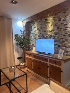 a living room with a tv on a stone wall at Casa Carmen I in Montoro