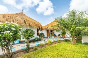 a villa with a thatched roof and a swimming pool at Tanema Creek in Brufut