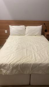 a white bed with white sheets and pillows at Apartamento ao lado do Mercado Central Edifício Fidelis in Goiânia