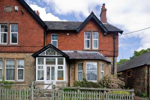 a brick house with a white fence in front of it at Monument View in Hexham