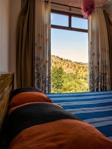 a bedroom with a window with a view of a mountain at Papa's Resort Dunhinda in Hinnarangahakumbura
