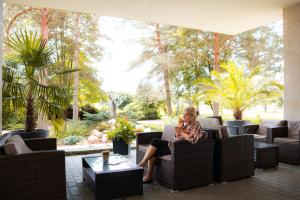 a woman sitting in a chair in a patio at Hotel Jantar Dudince in Dudince