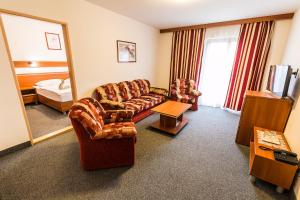 a hotel room with a couch and a bed and a mirror at Hotel Jantar Dudince in Dudince