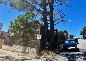 a car parked next to a fence with a tree at El Rinconcito de La Suiza in Robledo de Chavela