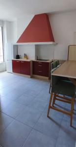 a large kitchen with a table and a red hood at Particulier & Pro - 4 chambres - 8 pers - Jaude avec parking privée in Clermont-Ferrand
