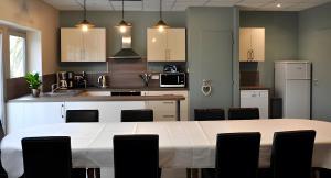 a kitchen with a large white table and chairs at Gîte La Maison Du Parc in Argilly