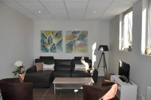a living room with a black couch and a table at Gîte La Maison Du Parc in Argilly