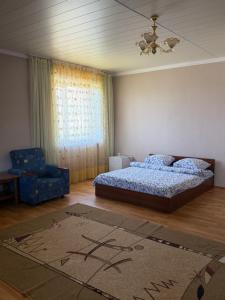 a bedroom with a bed and a chair and a rug at Алтын Мезгил in Korumdy