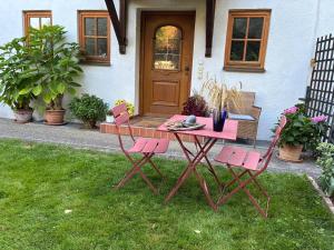 a pink table and chairs in front of a house at Schöne Souterrainwohnung in Seeshaupt in Seeshaupt