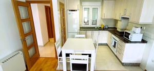 a kitchen with white cabinets and a table and chairs at EnSAN CIPRIAN Playas y Relax in San Ciprián