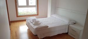a small white bed in a room with a window at EnSAN CIPRIAN Playas y Relax in San Ciprián